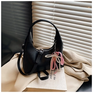 Détail du sac à main noir incurvé avec breloque nœud rose et décoration de perles