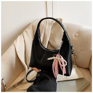 Détail du sac croissant noir avec nœud à carreaux rose et breloque en perles