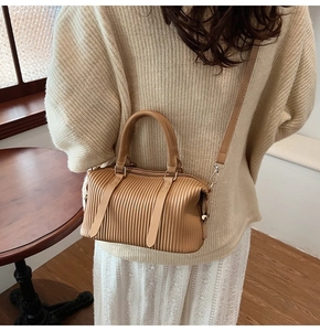 Detail of light brown pleated handbag with leather straps and matte PU texture