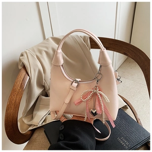 Détail d'un mini sac à main rose clair avec perles, nœud et accents métalliques en cœur