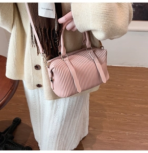 Pink pleated Boston bag with vertical textures and gold hardware shown in a lifestyle setting