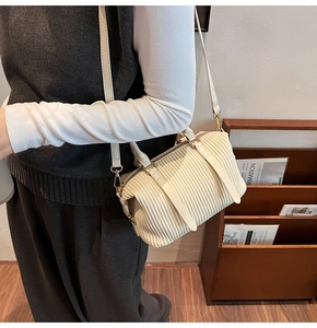 Detail of cream pleated crossbody bag with vertical textures and adjustable shoulder strap