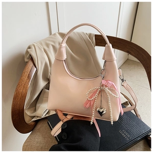 Détail du sac à main carré rose clair avec breloque perle et nœud en ruban à carreaux
