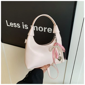 Détail du sac hobo rose clair avec charm nœud perlé et surface texturée épurée