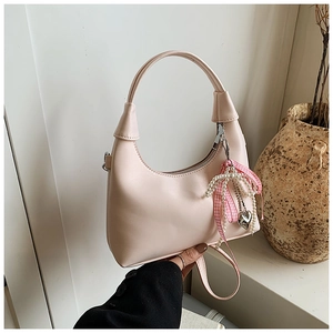 Détail d'un sac demi-lune rose orné de rubans décoratifs et d'un pendentif cœur perlé