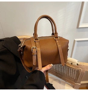 Detailed view of brown pleated texture handbag with golden hardware on a vintage chair