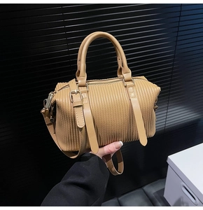 Close-up of beige pleated Boston bag with gold hardware and stylish decorative straps