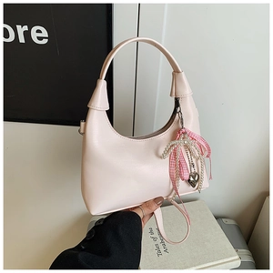 Détail d'un sac à main rose avec chaîne en perles et breloque noeud en cuir