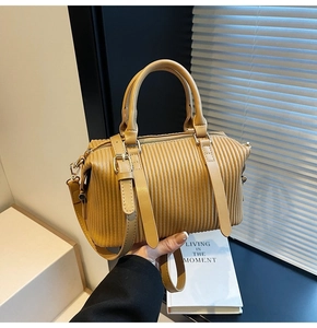 Close-up of brown pleated Boston bag with vertical organ folds and golden zipper hardware