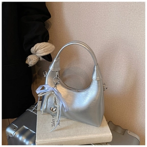 Détails d'un sac demi-lune argenté avec nœud, perles et pendentif en cœur