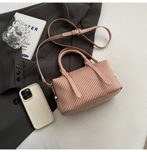 Detail showing pink pleated leather texture and golden metal buckle on a women handbag