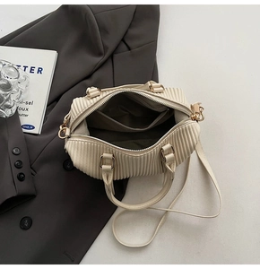Interior detail of beige pleated handbag with dark fabric lining and pocket