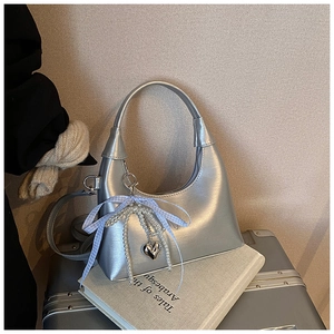Détail du sac à main argenté avec chaîne de perles, breloque cœur et nœud à carreaux