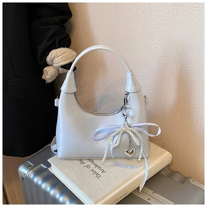 Détail du sac hobo bleu argenté avec breloque nœud en perles et pendentif cœur argenté