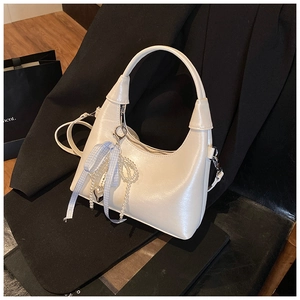 Détail du sac à main croissant blanc avec chaîne de perles, nœud bleu et pendentif cœur