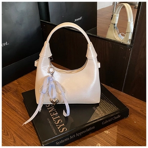 Détail d'un sac à main blanc crème orné de rubans de perles et d'un pendentif coeur