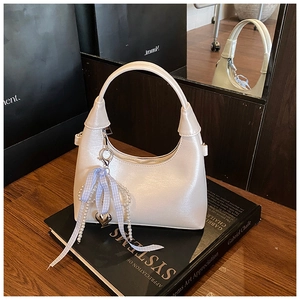 Détail du sac hobo blanc perle avec breloque nœud et pendentif cœur perle sur livre