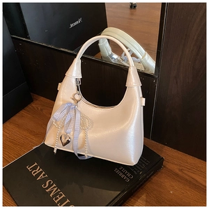 Détail du sac à main blanc perle avec breloque cœur et ruban à carreaux bleu chic