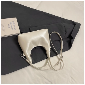 Vue détaillée du sac à main minimaliste blanc cassé avec poignée incurvée et texture en cuir
