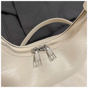 Détail macro des doubles fermetures éclair argentées sur le sac hobo en cuir crème