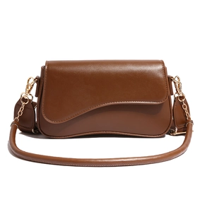 Sac bandoulière en cuir marron avec rabat incurvé et chaîne dorée sur fond blanc immaculé