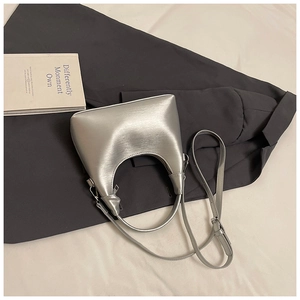 Gros plan d'un sac demi-lune argenté posé sur un blazer gris pour un look de bureau