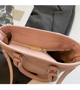 Detail of pink faux suede tote bag featuring smooth gold metal zipper and spacious interior