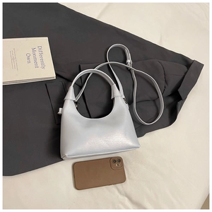 Vue détaillée d'un petit sac demi-lune bleu à côté d'un téléphone pour la taille