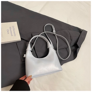 Détail du sac hobo demi-lune bleu clair avec bandoulière réglable sur fond texturé doux