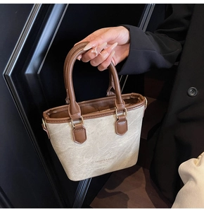 Detailed close-up of canvas and brown leather stitching on a stylish bucket bag