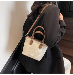 Detailed view of beige canvas tote with brown leather handles and adjustable shoulder strap