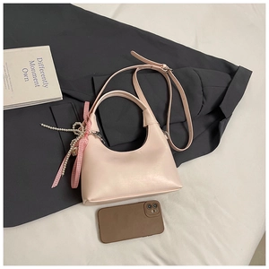 Détail du sac demi-lune rose clair avec nœud décoratif et élégante chaîne de perles