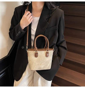 Chic beige and brown crossbody bucket bag styled with a professional black blazer outfit