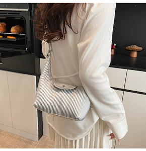 Detail of silver pleated crescent bag with metallic finish and magnetic snap closure