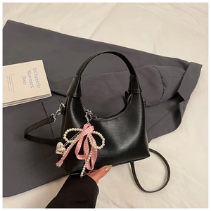Détail du petit sac à main en cuir noir avec nœud à carreaux rose et perles