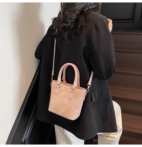 Close-up of pink suede crossbody bag with gold hardware and thin adjustable shoulder strap