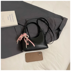 Détail d'un sac demi-lune noir avec nœud rose à carreaux et pendentif en perles