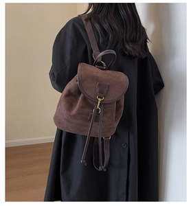 Detailed back view of a vintage brown suede backpack with drawstring and metal spring buckle