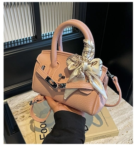 Detail der rosa Handtasche aus genarbtem Leder mit Silberschloss und dekorativem Seidentuch