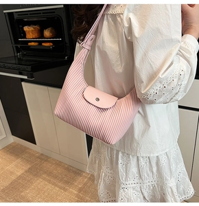 Detail of pink pleated crescent bag with leather flap closure and metallic button