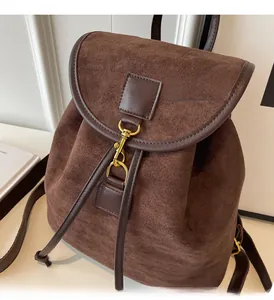 Close-up of vintage dark brown suede backpack with gold metal clasp and drawstring detail