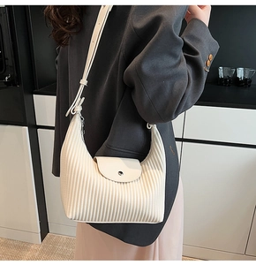 Detail of off-white pleated shoulder bag with vertical accordion texture and flap closure