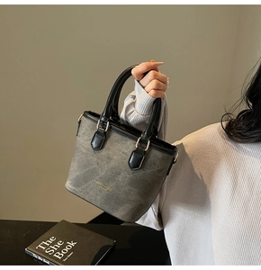 Close-up of grey textured leather tote with fashion gold logo and metal buckles