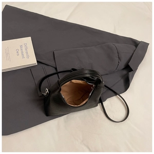 Vue de dessus du sac en cuir noir avec fermeture éclair argentée et doublure beige