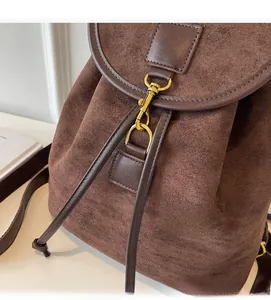 Close-up of caramel brown suede backpack featuring gold metal hooks and fine stitching detail
