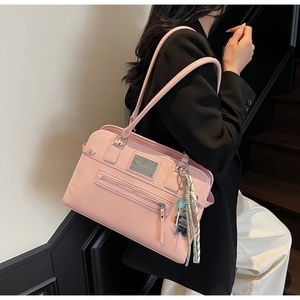 Detail of pink faux leather handbag with silver logo plaque and decorative bear charm
