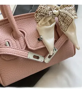 Detail der rosa Lederhandtasche mit silbernem Metallverschluss und einem Seidenschal