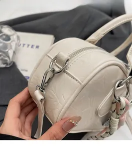 Gros plan du sac cylindrique blanc avec texture gaufrée et fermoirs argentés