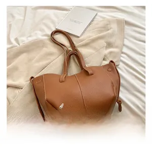 Détail du sac cabas marron à texture litchi avec nœud décoratif sur le côté