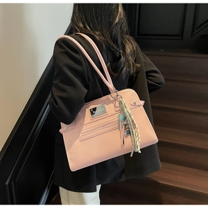 Detail view of pink leather underarm bag with metal logo and woven rope pendant charm